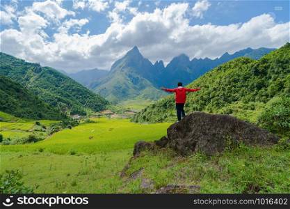 An Asian tourist man watching at Fansipan mountain hills with paddy rice agricultural field valley in summer in travel trip and holidays vacation concept, Sapa, Vietnam.