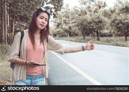 An asian woman get lost and hitchhiking for some car beside the street while traveling alone for summer trip in holidays and try to