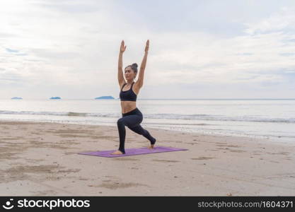An Asian woman in yoga class club doing exercise and yoga at natural beach and sea coast outdoor in sport and recreation concept. People lifestyle activity.
