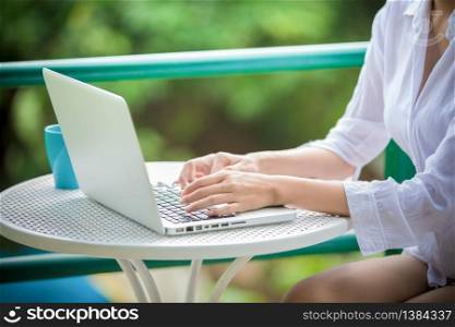 An Asian woman is using a notebook computer to work at home in the morning.