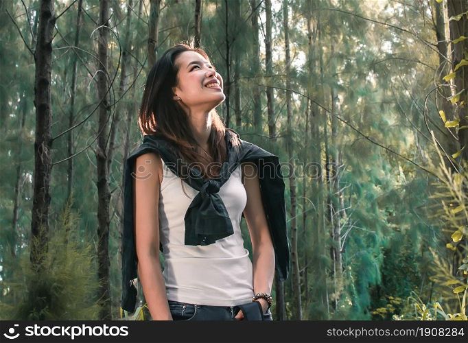 An asian woman smiling while traveling for camping in the forest with happiness. Nature and adventure concept.
