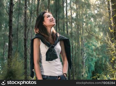 An asian woman smiling while traveling for camping in the forest with happiness. Nature and adventure concept.