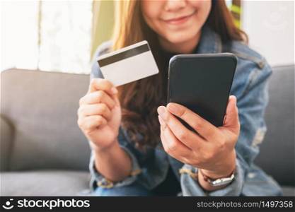 An asian woman using credit card for purchasing and shopping online on mobile phone