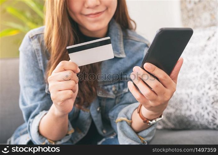 An asian woman using credit card for purchasing and shopping online on mobile phone