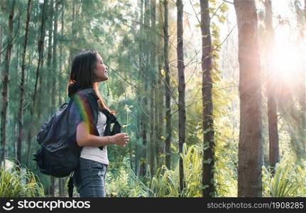 An asian woman with backpack smiling while traveling for camping in the forest with happiness. Nature and adventure concept.