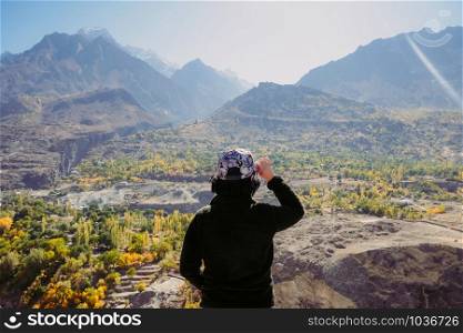 An Asian young traveler girl looking landscape mountainous scenery of beautiful valley in Karakoram mountain range, Gilgit Baltistan. Autumn season in northern Pakistan.