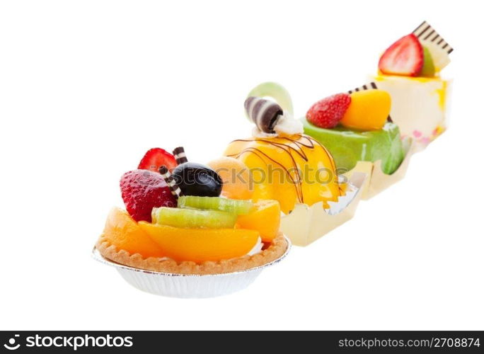 An assortment of Asian desserts, featuring (from left to right) Fruit Tart, Mango Mousse, Green Tea Cake, & Mousse Cake. Shot on white background.