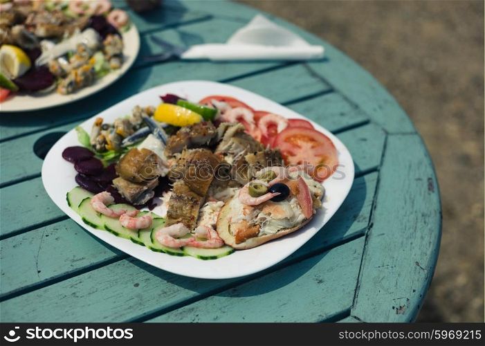 An assortment of crab, shellfish and fish on a plate outside