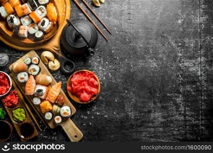 An assortment of different types of sushi and rolls. On dark rustic background. An assortment of different types of sushi and rolls.