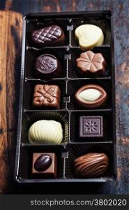 An assortment of fine chocolates in white, dark, and milk chocolate on wooden board