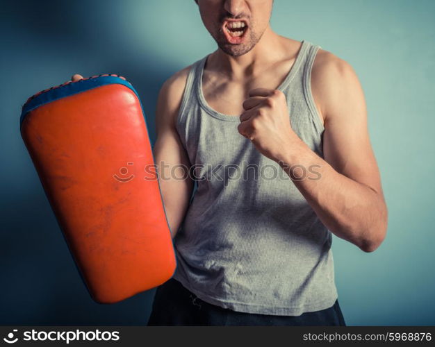 An athletic young man is holding pads and is ready for some muay thai or mixed martial arts training