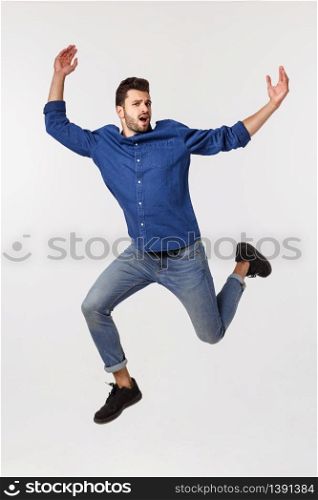An attractive athletic businessman jumping up against white background.. An attractive athletic businessman jumping up against white background
