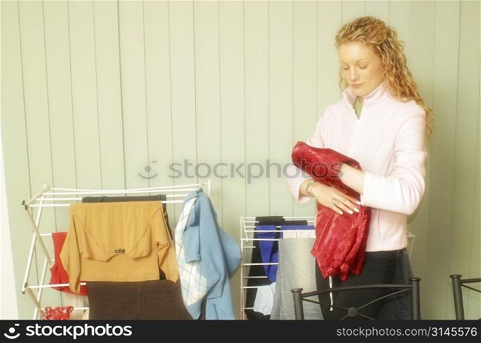 An attractive blonde woman at home in the kitchen dong house hold chores.
