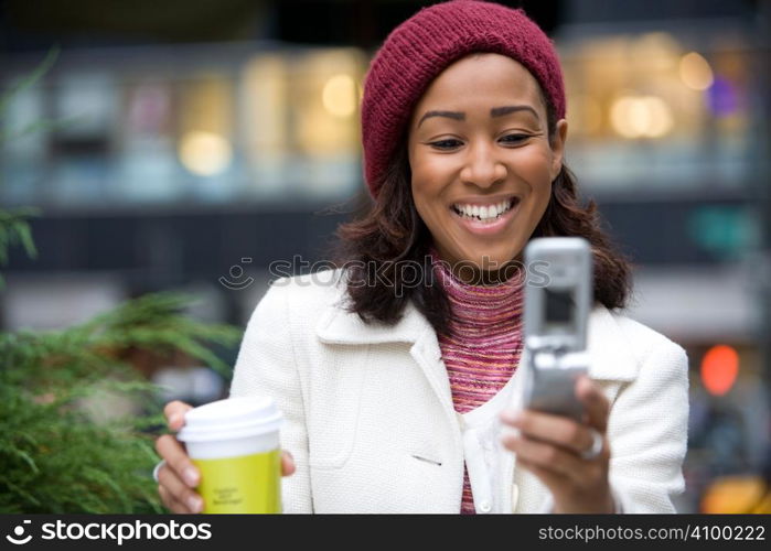 An attractive business woman checking her cell phone in the city. She could be text messaging or even browsing the web via wi-fi or a 3g connection.