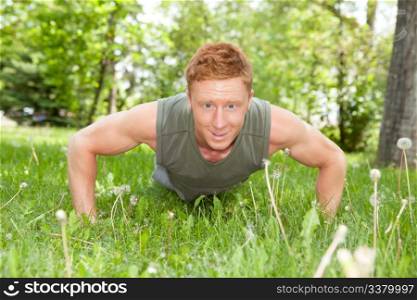 An attractive Caucasian man doing a push up outdoors