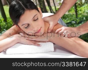 An attractive Caucasian woman getting massaged by a therapist