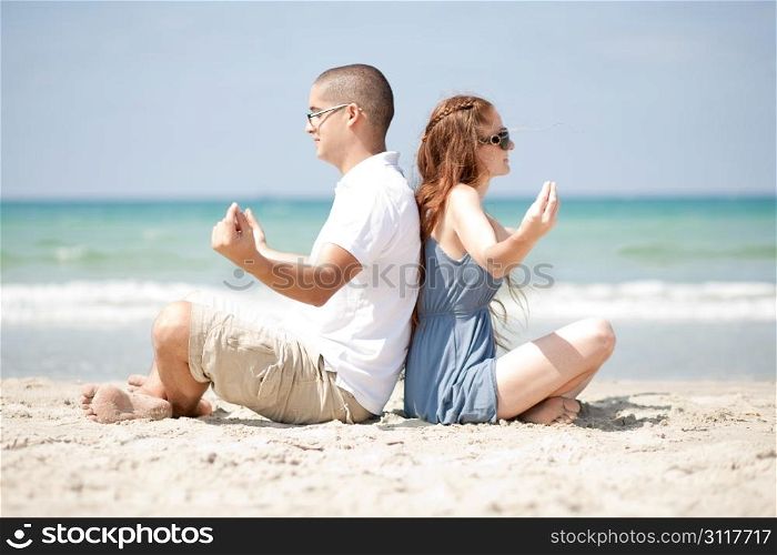 An attractive couple Meditating at the beach