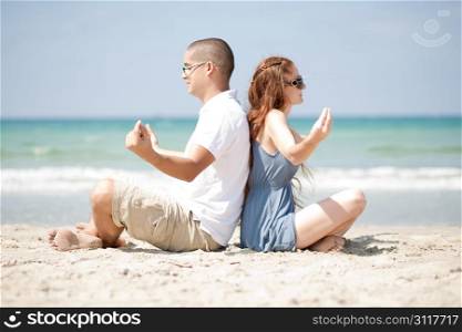An attractive couple Meditating at the beach