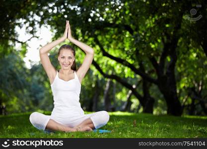 An attractive girl in a pose of yoga outdoors