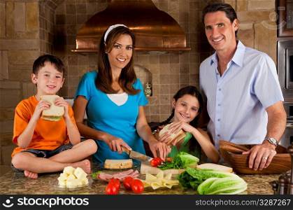 An attractive happy, smiling family of mother, father, son and daughter making healthy sandwiches with ham, cheese and fresh salad in a modern kitchen