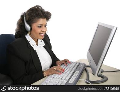 An attractive Indian technical support specialist sitting at the computer with a headset on. Isolated on white.