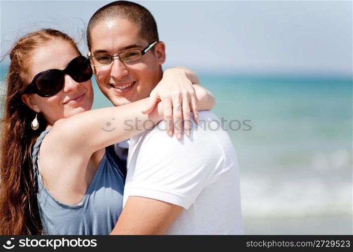 An attractive loving couple together at the beach