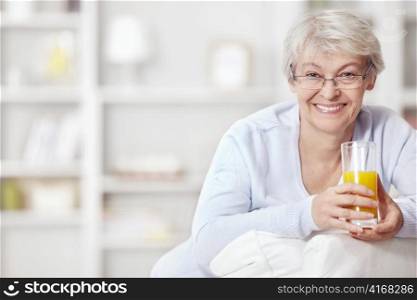 An attractive middle-aged woman with a glass of juice at home