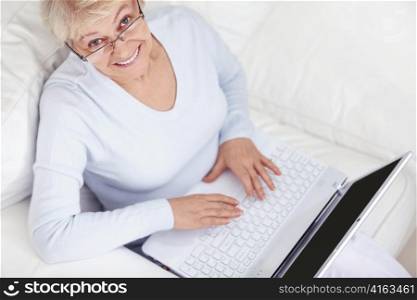 An attractive middle-aged woman with a laptop on a white sofa