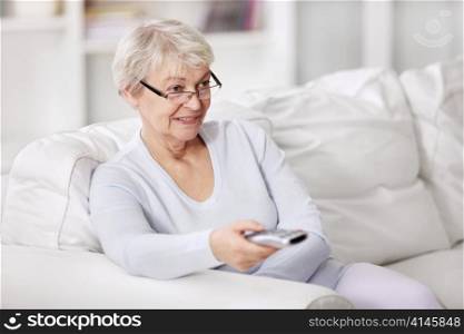 An attractive older woman switches TV channels