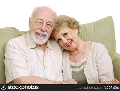 An attractive senior couple at home on the couch together. Isolated on white.
