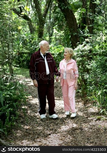 An attractive senior couple strolling through the park hand in hand.