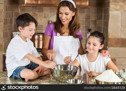An attractive smiling family of mother and two children, girl boy, son daughter, baking in a kitchen at home