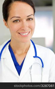 An attractive smiling female doctor wearing a white coat and stethoscope in a hospital.
