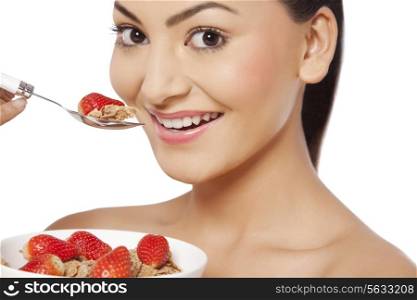 An attractive young woman eating cornflakes with strawberries