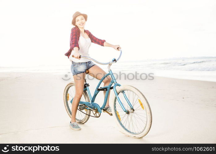 An attractive young woman riding her bicycle on the beach