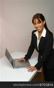 An attractive young woman working on a computer using a mouse.