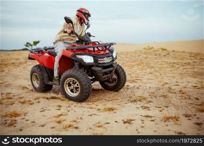 An atv rider racing in desert, downhill riding in desert sands, action view. Male person on quad bike, sandy race, dune safari in hot sunny day, 4x4 extreme adventure, quad-biking concept. An atv rider racing in desert