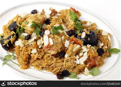 An authentic Saudi chicken kabsa (known in Qatar as majbous), garnished with raisins and toasted almond flakes, on a serving bowl at and angle. Kabsa is a national staple for Saudi Arabia and the Arab Gulf States.