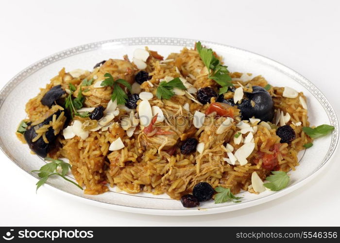 An authentic Saudi chicken kabsa (known in Qatar as majbous), garnished with raisins and toasted almond flakes, on a serving bowl. Kabsa is a national staple for Saudi Arabia and the Arab Gulf States.