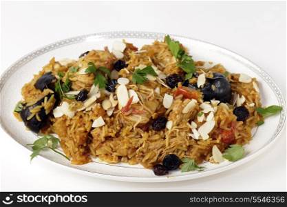 An authentic Saudi chicken kabsa (known in Qatar as majbous), garnished with raisins and toasted almond flakes, on a serving bowl. Kabsa is a national staple for Saudi Arabia and the Arab Gulf States.