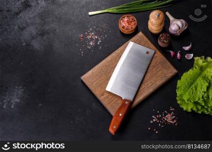 An axe for meat, spices and herbs, a cutting board against a dark concrete background. Cooking at home. An axe for meat, spices and herbs, a cutting board against a dark concrete background