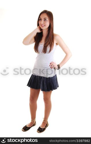 An beautiful teenager standing in a short skirt and gray t-shirt, withher long brunette hair, over white background.