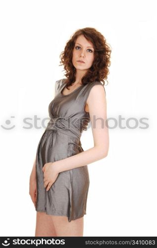An beautiful young and slim woman standing in a short silver dressand high heels, on white background.