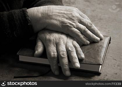 An black-and-white image of old woman's hands on Bible