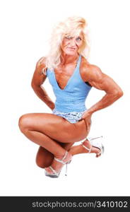 An blond bodybuilding girl kneeling on the floor of a studio and shooingher very muscular body with high heels and blouse top and shorts, over white.