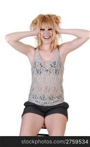 An blond greasy woman, sitting on a chair in the studio, in shorts anda lace top messing up her hair, for white background.