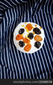 An Easter cake decorated with dried apricots and prunes stands on a blue striped apron. Easter religious holiday concept, top view. An Easter cake decorated with dried apricots and prunes stands on a blue striped apron. Easter religious holiday concept, top view.