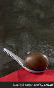 An Easter egg in a spoon on a slate background