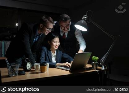 An elderly business man is advising company employees at the office during overtime, Three businessmen are discussing and solving work problems at the office at night.