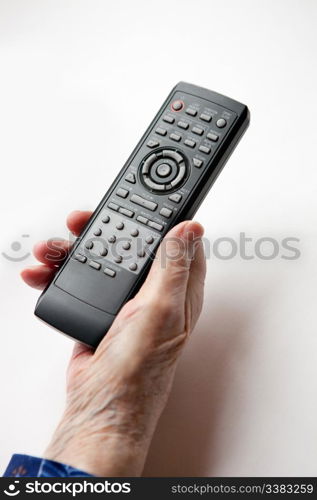 An elderly hand with a TV DVD remote control